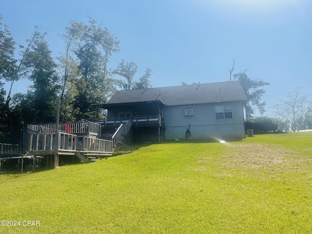 back of property featuring central AC, a deck, and a lawn