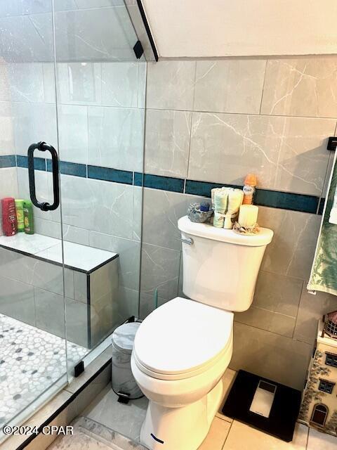 full bathroom featuring toilet, a shower stall, and tile walls