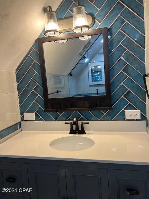 bathroom featuring visible vents, decorative backsplash, vanity, and tile walls