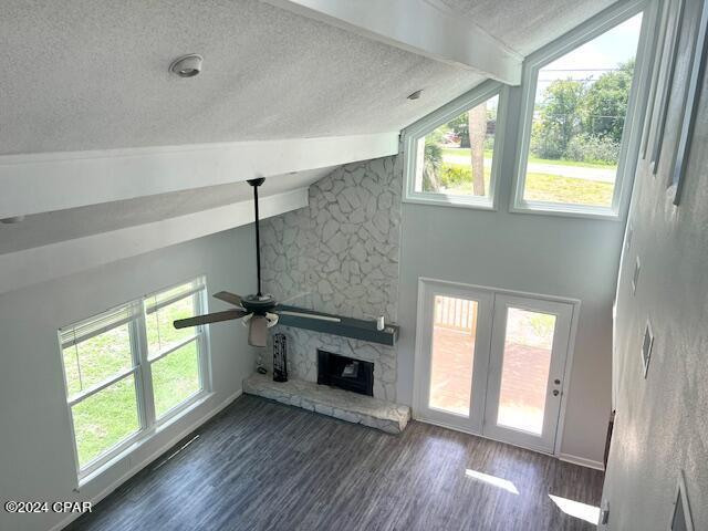 unfurnished living room featuring a textured ceiling, high vaulted ceiling, a fireplace, and wood finished floors