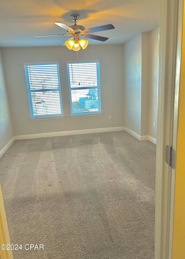 carpeted spare room with a wealth of natural light and ceiling fan