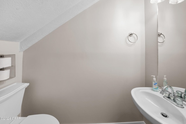 bathroom featuring a textured ceiling, toilet, and sink