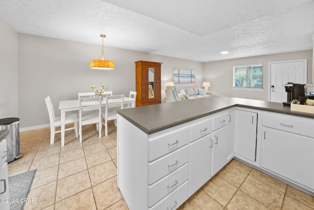 kitchen featuring kitchen peninsula, white cabinetry, light tile patterned floors, and decorative light fixtures