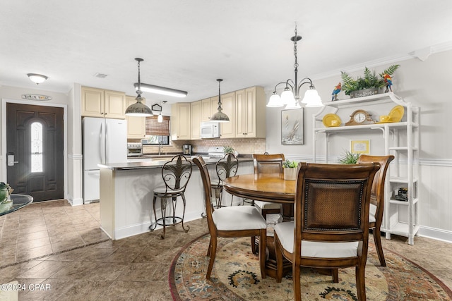 dining space featuring ornamental molding, sink, and a chandelier