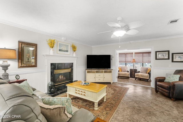 tiled living room featuring crown molding, a tile fireplace, and ceiling fan