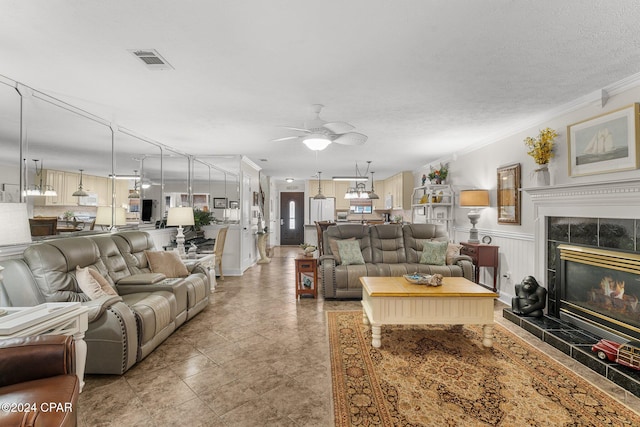 living room featuring crown molding, a textured ceiling, a tile fireplace, and ceiling fan