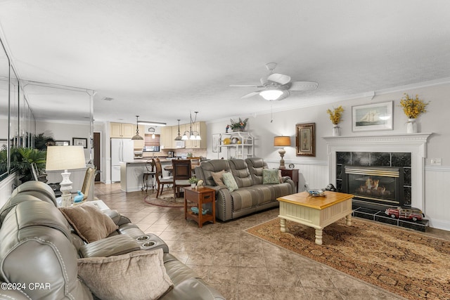 living room featuring ornamental molding, a tile fireplace, and ceiling fan