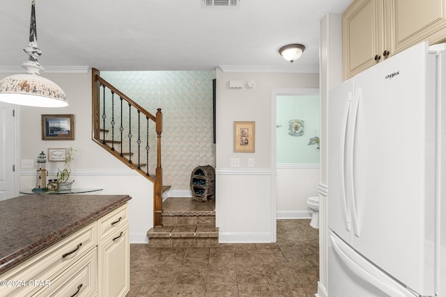 kitchen with ornamental molding, hanging light fixtures, cream cabinetry, and white refrigerator