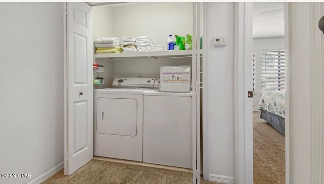 laundry room with washer and clothes dryer and light colored carpet