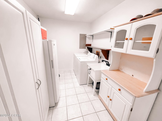 laundry area featuring light tile patterned flooring, cabinets, and separate washer and dryer