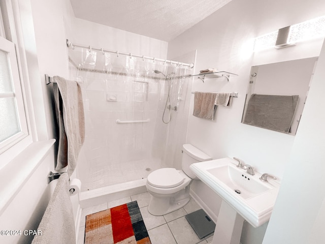 bathroom with tile patterned floors, a textured ceiling, toilet, and walk in shower