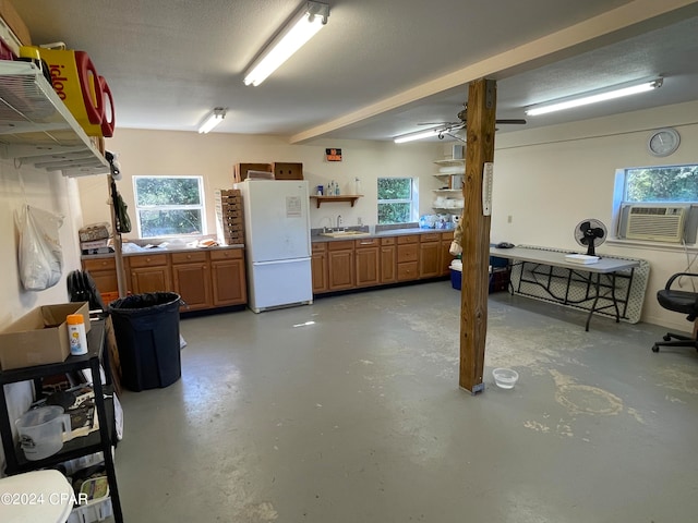 basement featuring cooling unit, a textured ceiling, sink, and white refrigerator