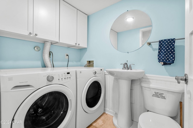 clothes washing area with washing machine and clothes dryer, sink, and light tile patterned floors