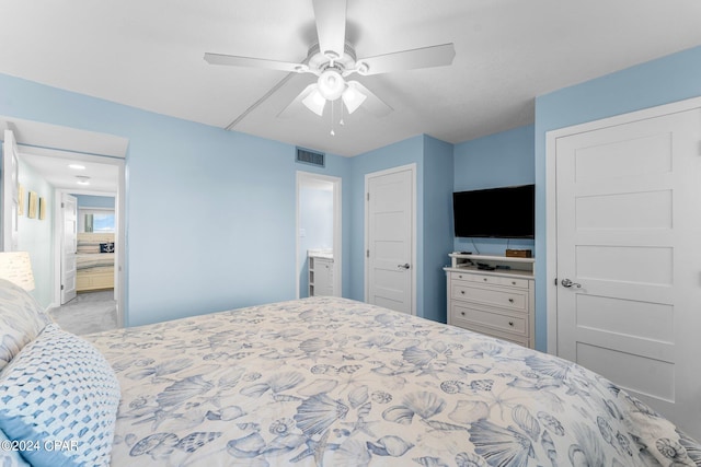 bedroom featuring ceiling fan, ensuite bathroom, and light carpet