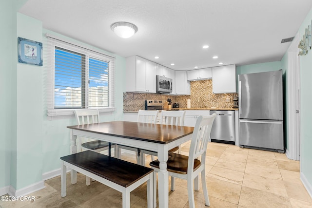 kitchen with decorative backsplash, white cabinets, stainless steel appliances, and a textured ceiling