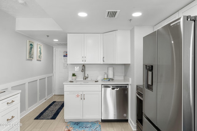 kitchen featuring sink, white cabinets, stainless steel appliances, and light wood-type flooring