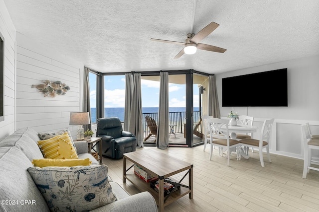 living room with expansive windows, a textured ceiling, light hardwood / wood-style floors, and ceiling fan