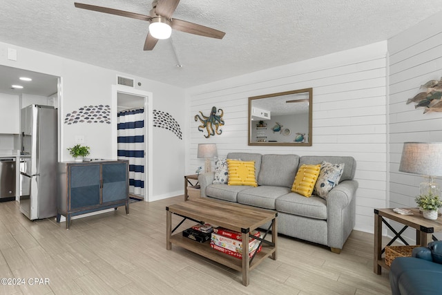 living room featuring light hardwood / wood-style flooring, a textured ceiling, and ceiling fan