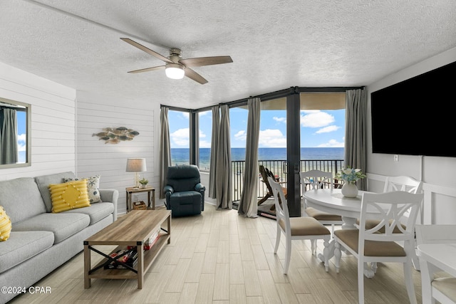 living room with light hardwood / wood-style floors, a textured ceiling, and a healthy amount of sunlight