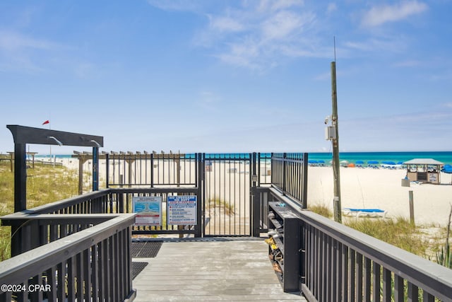 wooden deck featuring a water view and a beach view