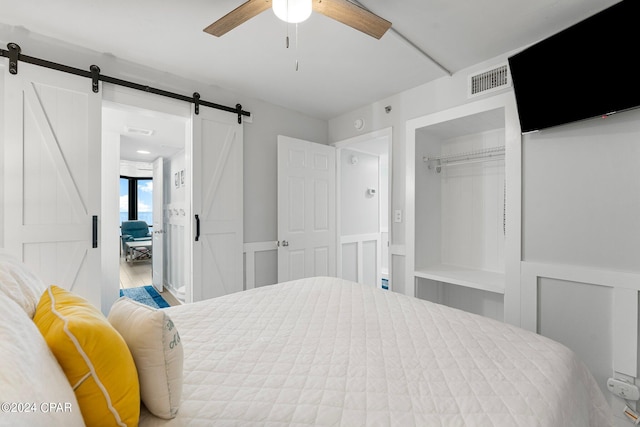 bedroom with a barn door, a closet, and ceiling fan