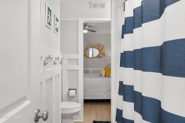 bathroom featuring toilet, wood-type flooring, a shower with curtain, and ceiling fan