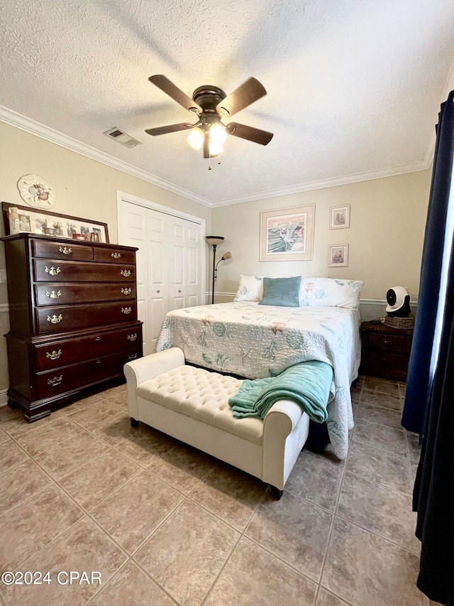 tiled bedroom with ceiling fan, a closet, a textured ceiling, and ornamental molding