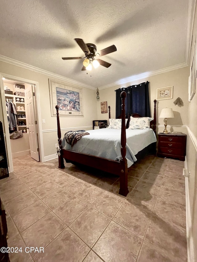 bedroom featuring crown molding, ceiling fan, a spacious closet, a textured ceiling, and a closet