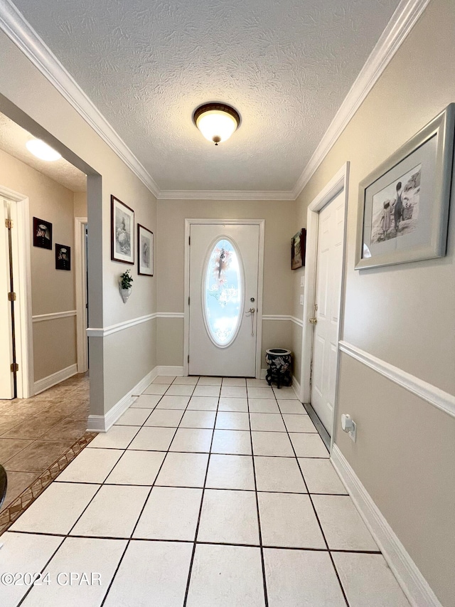 foyer with light tile patterned floors, a textured ceiling, and ornamental molding