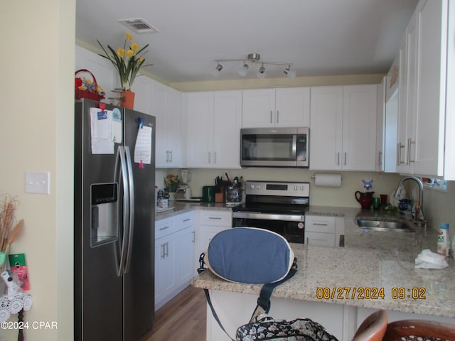 kitchen featuring white cabinetry, sink, light hardwood / wood-style floors, and appliances with stainless steel finishes