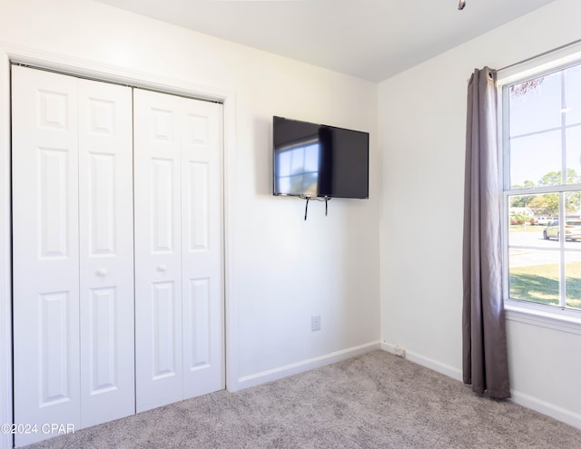 unfurnished bedroom featuring light colored carpet and a closet