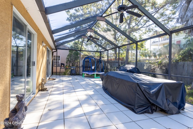 view of patio featuring a trampoline and glass enclosure