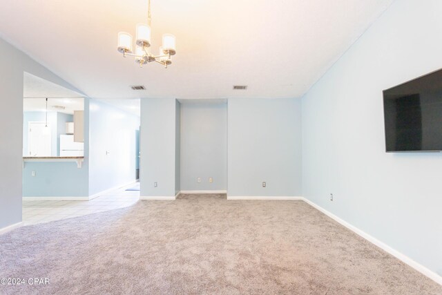 spare room featuring a notable chandelier and light colored carpet