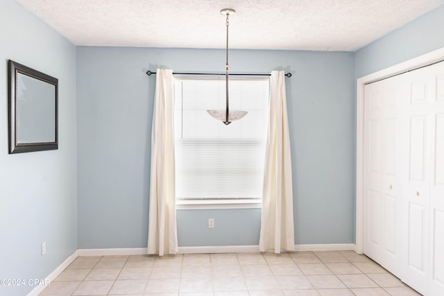 unfurnished dining area featuring a textured ceiling and light tile patterned flooring