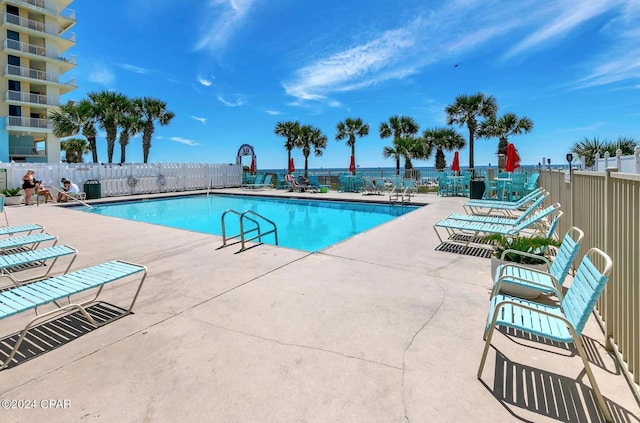 view of swimming pool featuring a water view and a patio