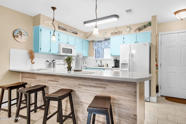 kitchen with blue cabinetry, kitchen peninsula, a breakfast bar area, and white appliances