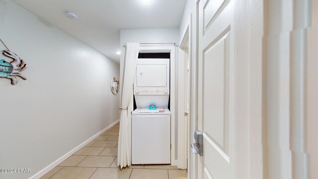 clothes washing area with stacked washer / dryer and light tile patterned floors