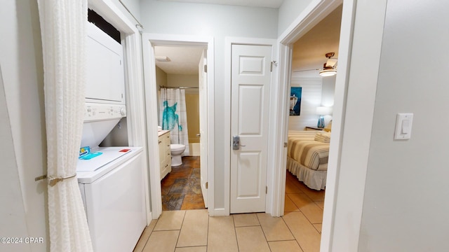 washroom featuring light tile patterned floors and stacked washer and clothes dryer