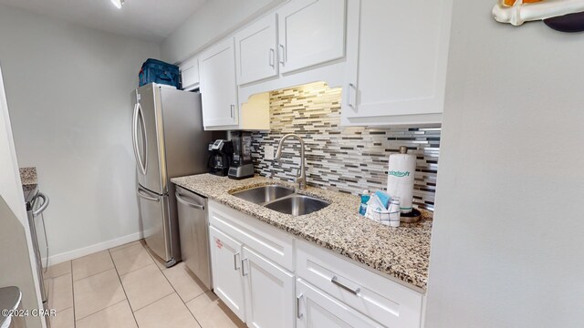 kitchen featuring decorative backsplash, light stone counters, white cabinetry, sink, and stainless steel appliances