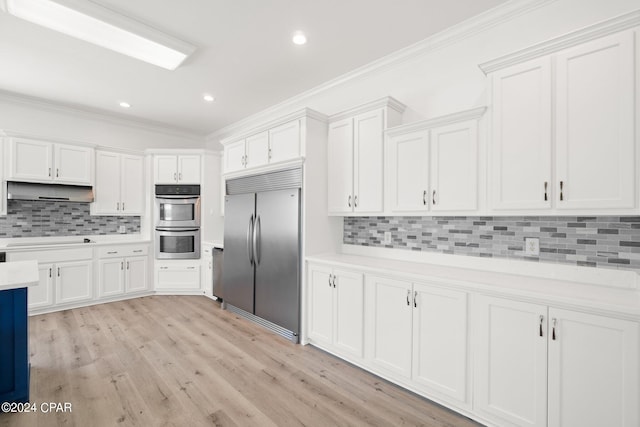 kitchen with light wood-type flooring, crown molding, stainless steel appliances, backsplash, and white cabinetry