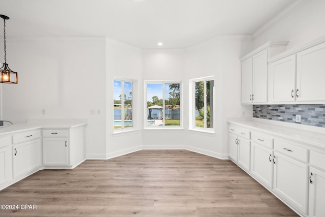 interior space with tasteful backsplash, light wood-type flooring, pendant lighting, and white cabinets