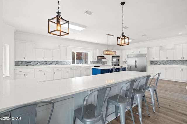 kitchen with pendant lighting, white cabinetry, a spacious island, appliances with stainless steel finishes, and backsplash