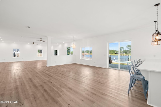 unfurnished living room with ceiling fan with notable chandelier and light hardwood / wood-style floors