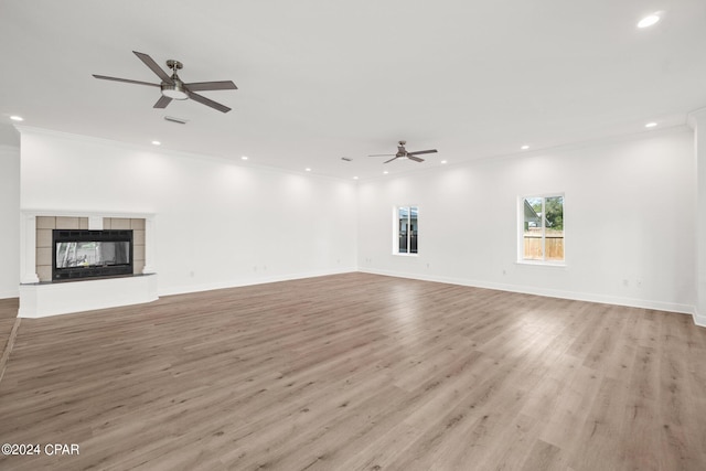 unfurnished living room featuring a fireplace, light hardwood / wood-style floors, ornamental molding, and ceiling fan