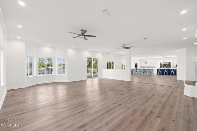 unfurnished living room with light hardwood / wood-style floors, crown molding, and ceiling fan