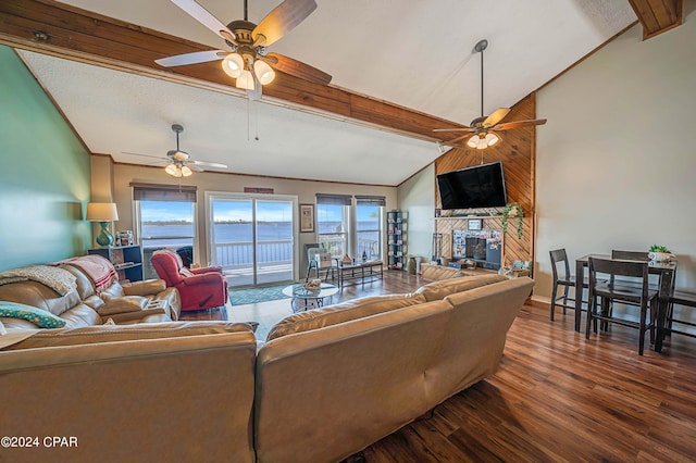 living room with vaulted ceiling with beams, dark wood-type flooring, a large fireplace, a textured ceiling, and ceiling fan