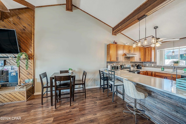 kitchen with appliances with stainless steel finishes, a notable chandelier, lofted ceiling with beams, and dark hardwood / wood-style flooring