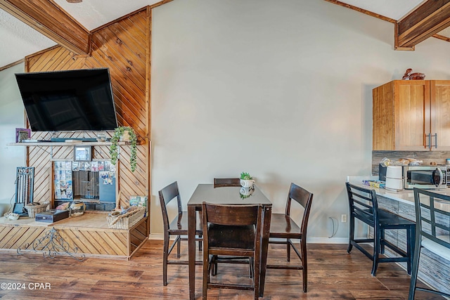 dining room featuring lofted ceiling with beams, wood-type flooring, ornamental molding, and a multi sided fireplace