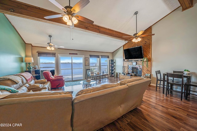 living room featuring vaulted ceiling with beams, ceiling fan, a large fireplace, dark wood-type flooring, and baseboards