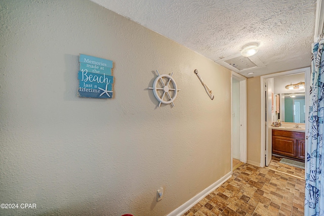 corridor with sink and a textured ceiling